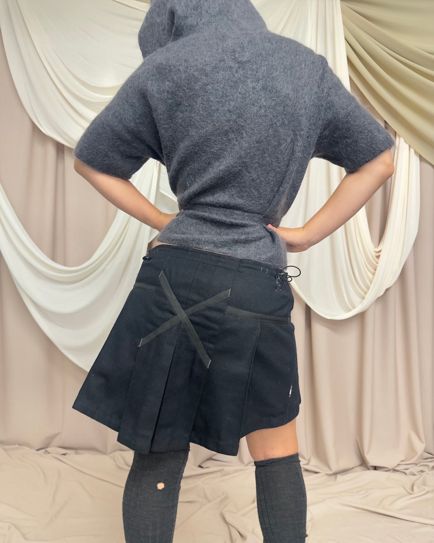 BLACK WOOL PLEATED MINI SKIRT WITH CROSS FRONT DETAIL by Maharishi