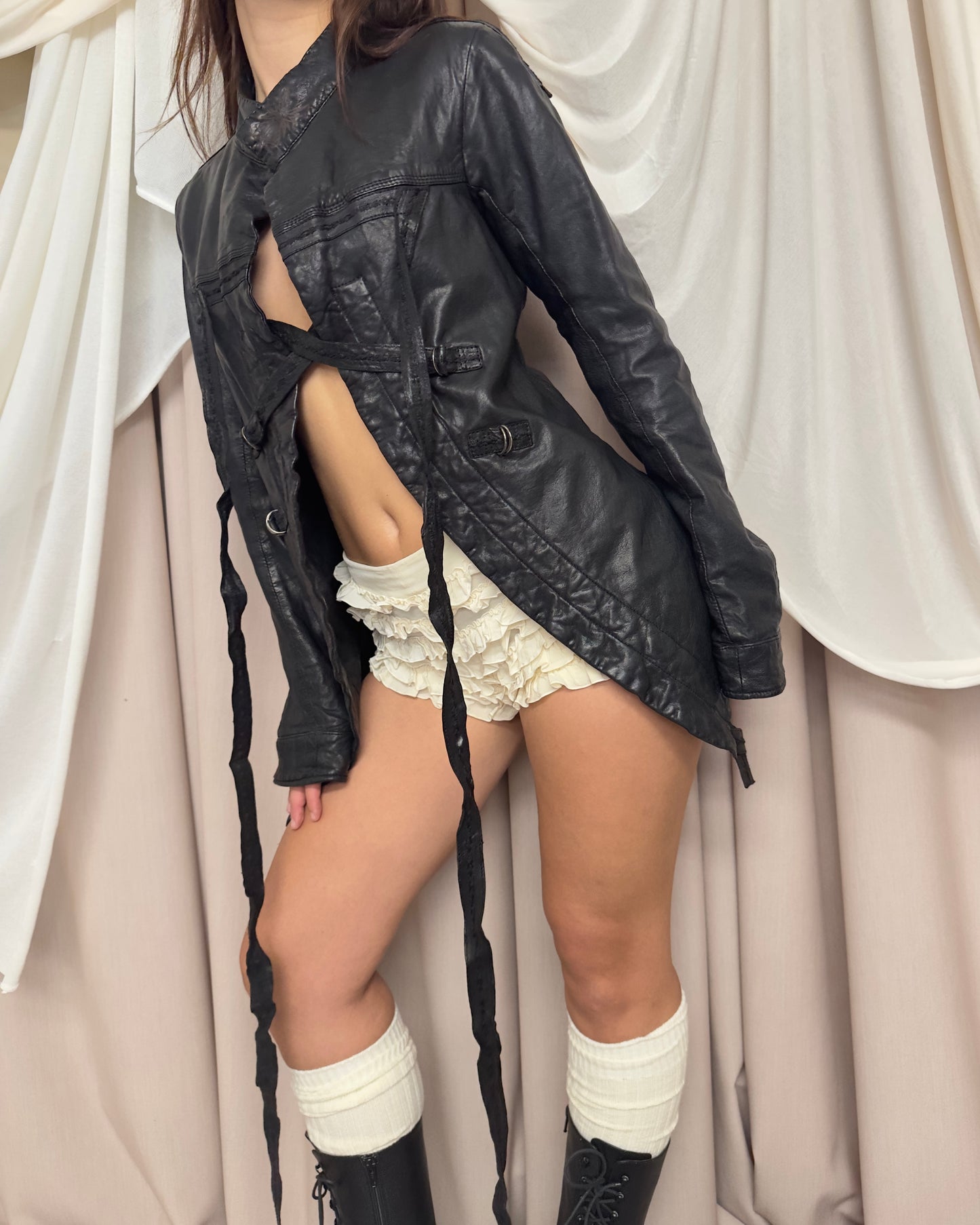 BLACK LEATHER 'BONDAGE' JACKET WITH ASYMMETRICAL HEM AND UTILITARIAN STRAPS by Marithé + François Girbaud